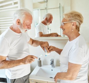Two seniors brushing their teeth.